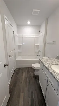 a bathroom with a granite countertop toilet a sink and a shower