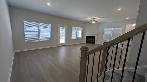 a view of a livingroom with wooden floor a ceiling fan and windows