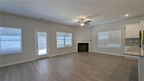 an empty room with windows chandelier fan and fireplace