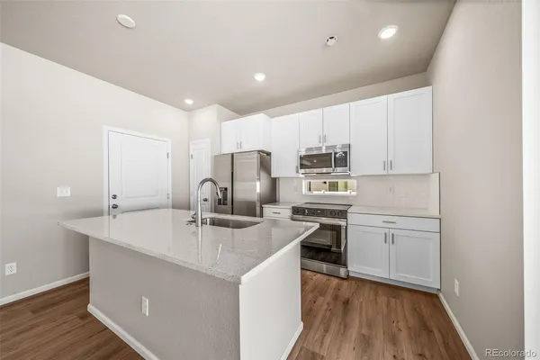 a kitchen with a sink a stove a refrigerator and white cabinets