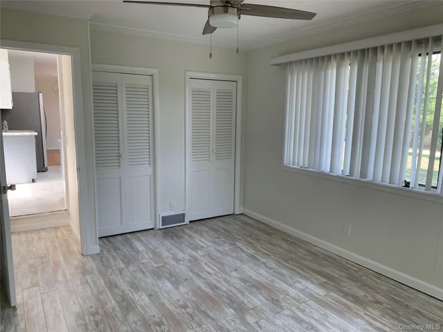 an empty room with wooden floor cabinet and windows