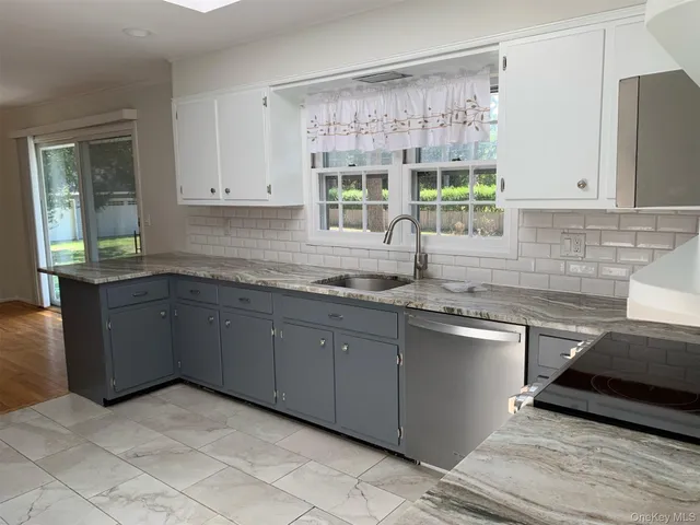 a kitchen with granite countertop a sink window and cabinets