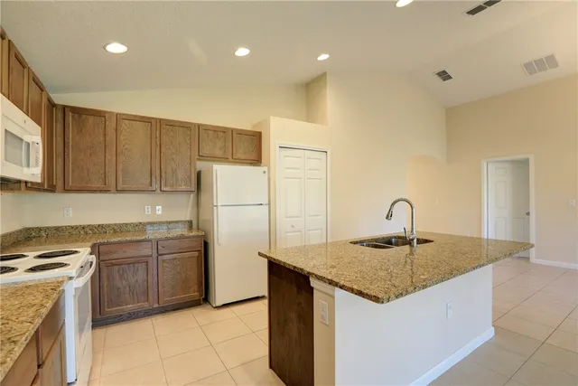 a kitchen with a refrigerator a stove top oven a sink and cabinets