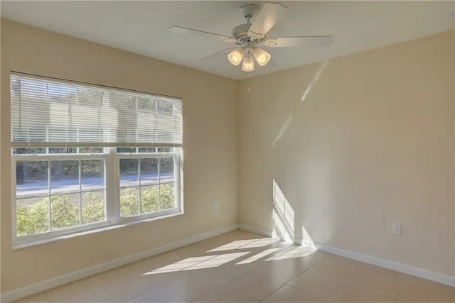 an empty room with a chandelier fan and windows