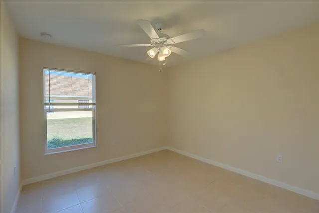 an empty room with a ceiling fan and a window
