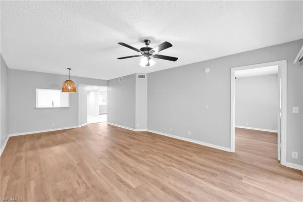 a view of an empty room with window and chandelier fan