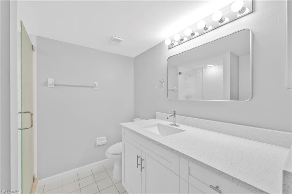 7791 Esmeralda Way, Unit L103 Naples, FL 34109 - Photo 20 of 22 a bathroom with a sink a toilet and a mirror