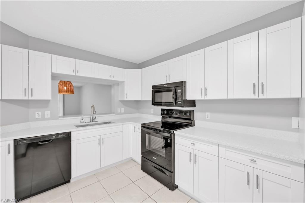 7791 Esmeralda Way, Unit L103 Naples, FL 34109 - Photo 5 of 22 a kitchen with white cabinets stainless steel appliances and sink