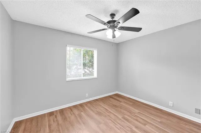 an empty room with wooden floor fan and windows