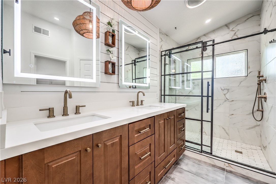 1900 Cardinal Point Street Henderson, NV 89012 - Photo 4 of 32 A refined bathroom featuring a double vanity with warm wooden cabinetry and a spacious walk-in shower.