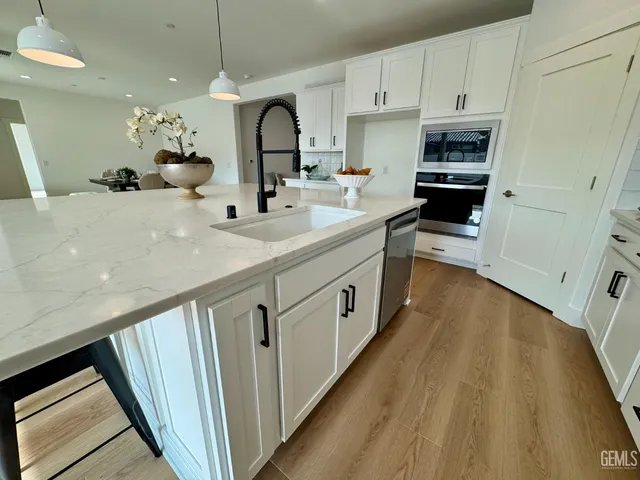 a kitchen with counter top space a sink wooden floor and stainless steel appliances