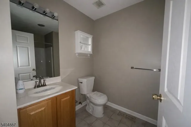 a bathroom with a granite countertop toilet a sink and a mirror