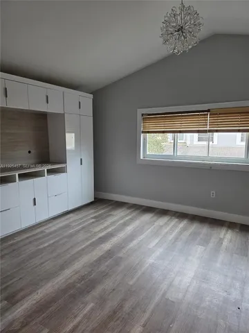 a view of an empty room with a window and a kitchen