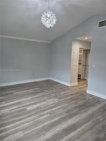 a view of empty room with wooden floor and ceiling fan