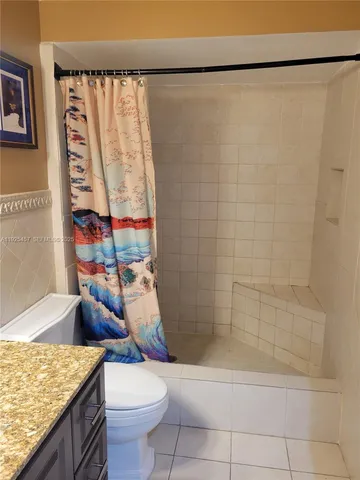 a bathroom with a granite countertop sink a toilet and shower