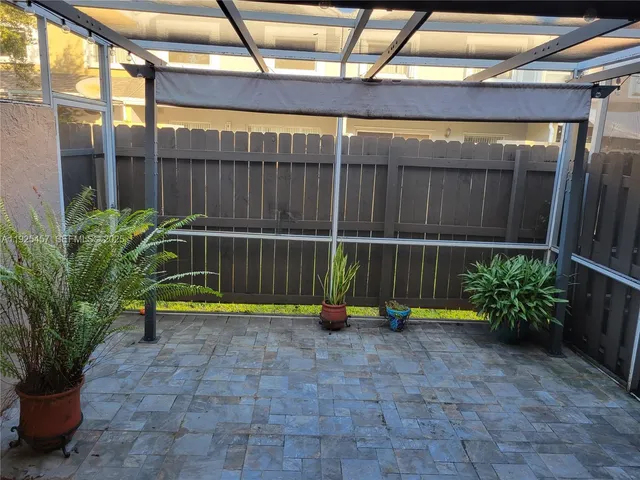 a view of a backyard with couches plants and wooden fence