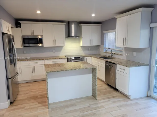 a kitchen with stainless steel appliances granite countertop a sink a stove a refrigerator and cabinets