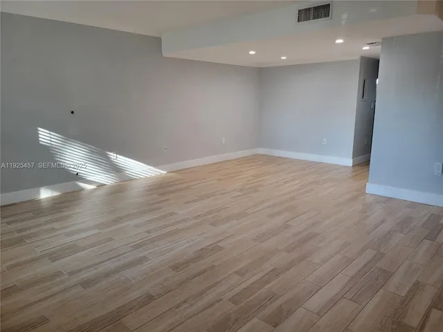 a view of empty room with wooden floor