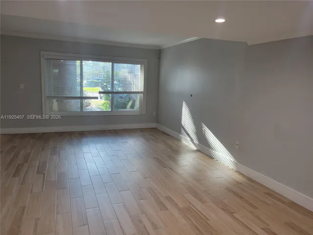 an empty room with wooden floor and a window