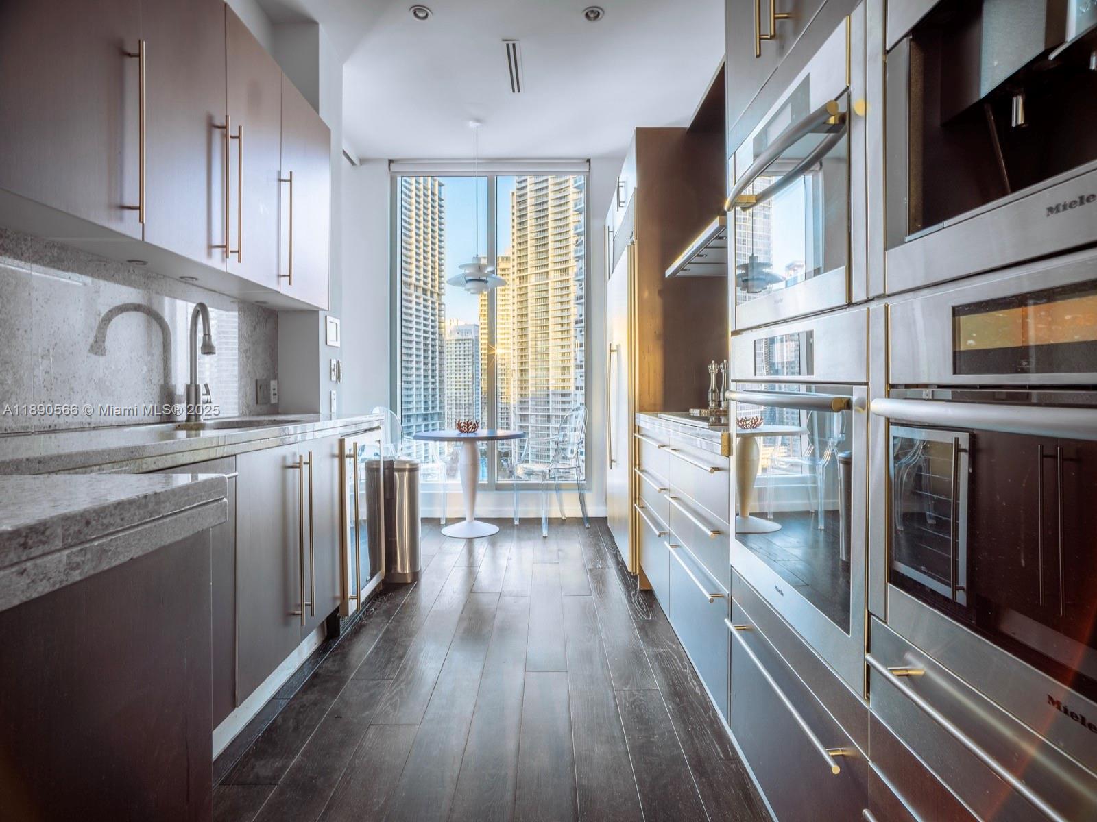 900 Brickell Key Boulevard, Unit 2204 Miami, FL 33131 - Photo 8 of 40 a kitchen with stainless steel appliances a stove top oven and wooden floors