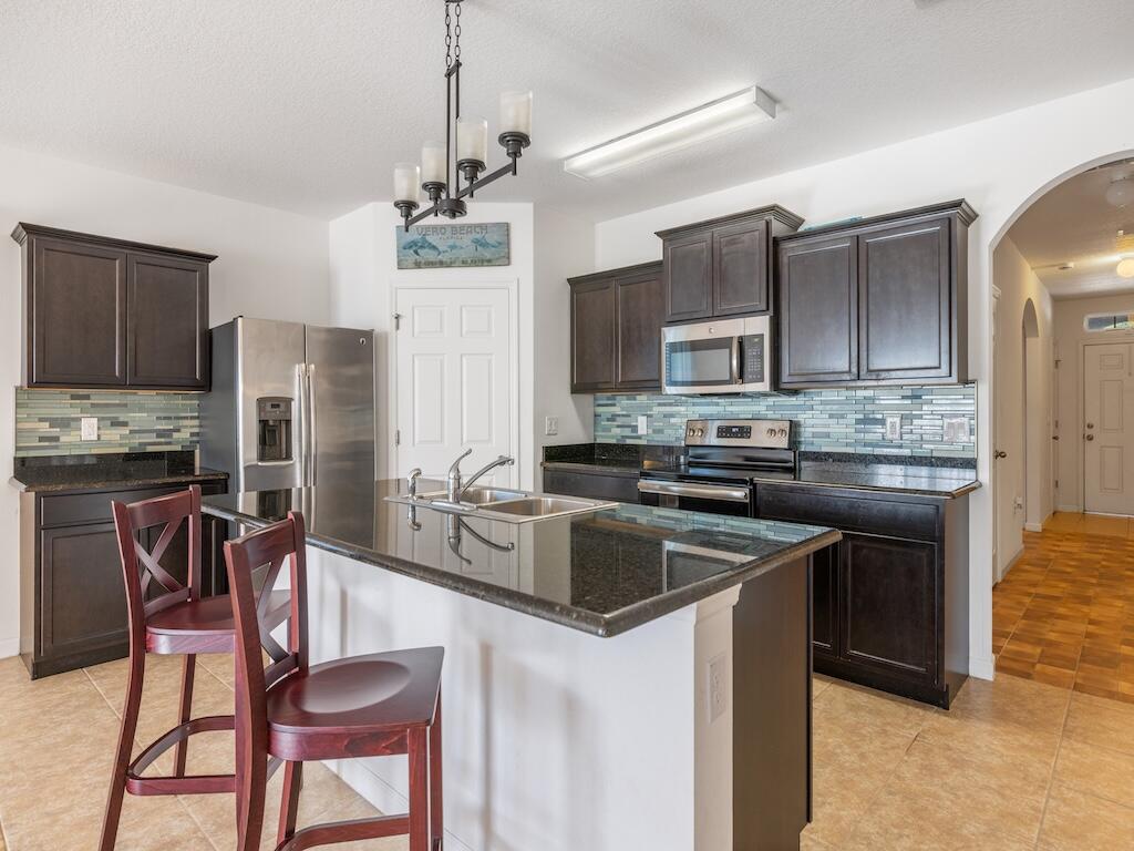 1440 Lexington Square Southwest Vero Beach, FL 32962 - Photo 2 of 41 a kitchen with stainless steel appliances granite countertop a stove a sink a microwave and a refrigerator