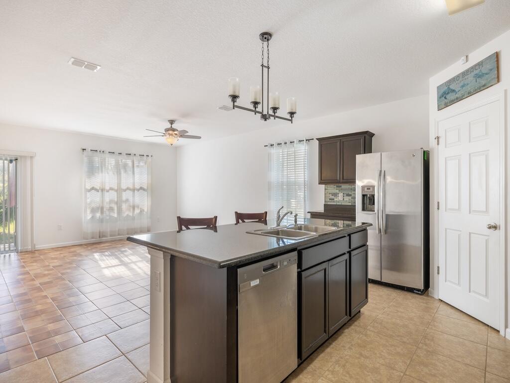 1440 Lexington Square Southwest Vero Beach, FL 32962 - Photo 5 of 41 a kitchen with stainless steel appliances granite countertop a sink a stove a refrigerator cabinets and a dining table