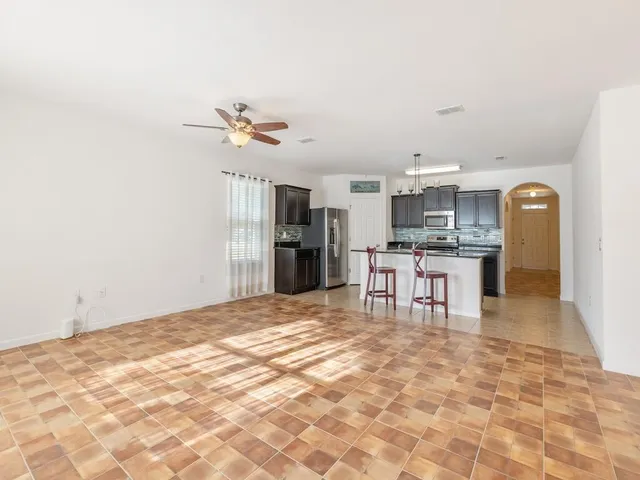 a living room with stainless steel appliances kitchen island granite countertop a refrigerator and a stove top oven