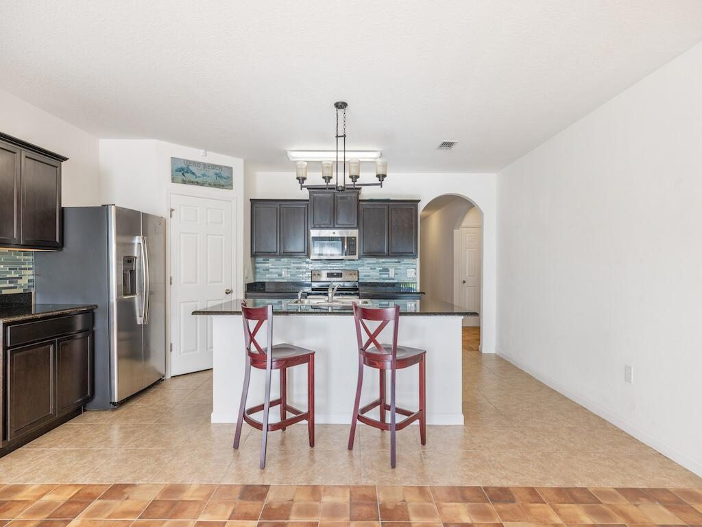 1440 Lexington Square Southwest Vero Beach, FL 32962 - Photo 10 of 41 a kitchen with stainless steel appliances kitchen island granite countertop a dining table chairs and granite counter tops
