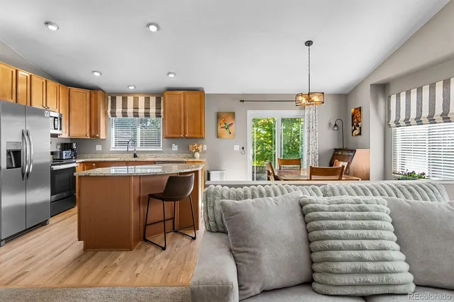 a living room with kitchen island granite countertop furniture a large window and stainless steel appliances