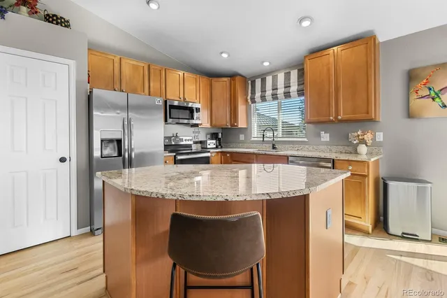 a kitchen with stainless steel appliances granite countertop a table chairs sink refrigerator and cabinets