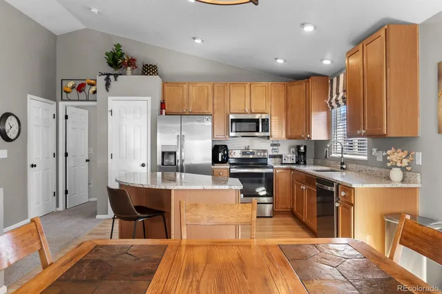 a kitchen with stainless steel appliances a stove a sink a refrigerator white cabinets and wooden floor