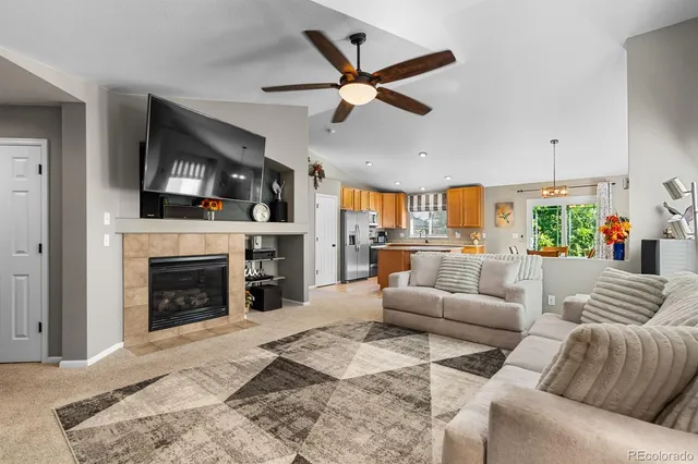 a living room with furniture a fireplace and a ceiling fan