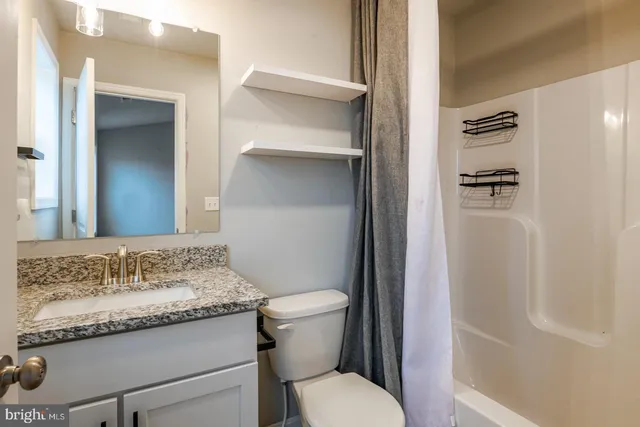 a bathroom with a granite countertop sink toilet and shower