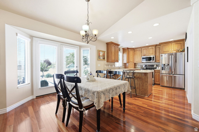776 Flint Street Layton, UT 84041 - Photo 10 of 41 Open-concept living space featuring wood-finish flooring, a kitchen island with seating, stainless steel appliances, and a bay window