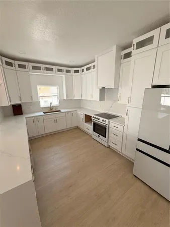 a large white kitchen with a stove a sink dishwasher and a refrigerator