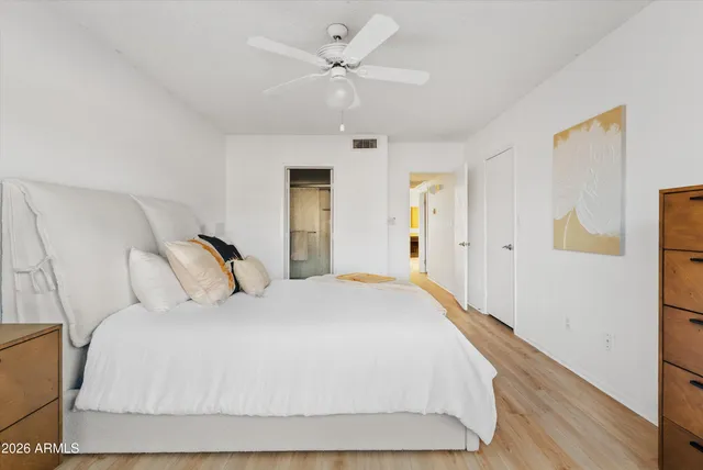 a spacious bedroom with a bed and wooden floor