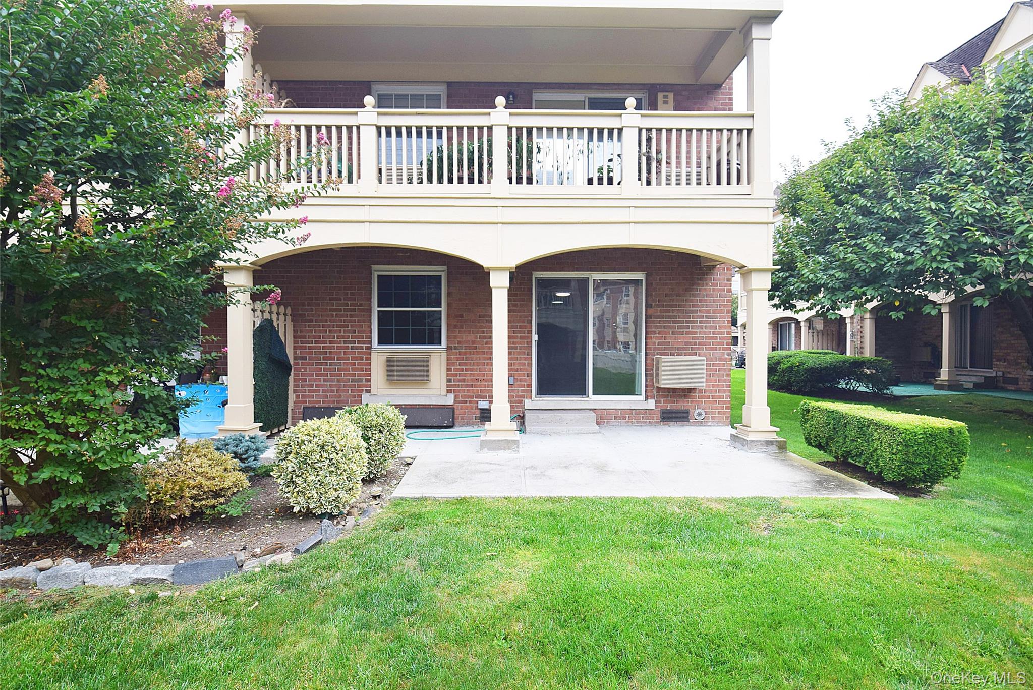 12-36 Estates Lane, Unit 49L Queens, NY 11360 - Photo 35 of 37 a front view of a house with a garden and porch