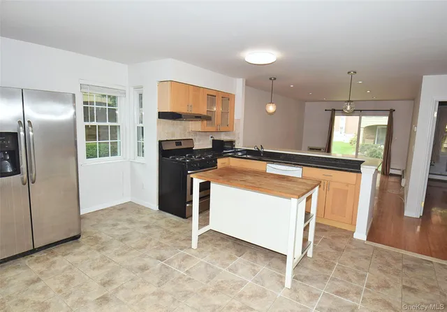 a kitchen with stainless steel appliances granite countertop a refrigerator a stove and a sink