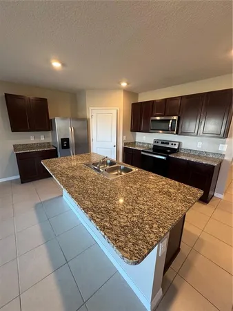 a kitchen with kitchen island granite countertop a sink stove and microwave