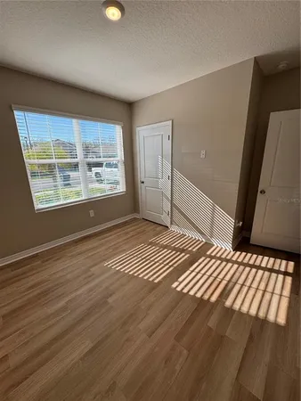 a view of an empty room with wooden floor and a window
