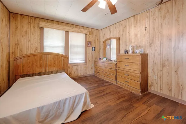 a bedroom with a bed dresser and a large window
