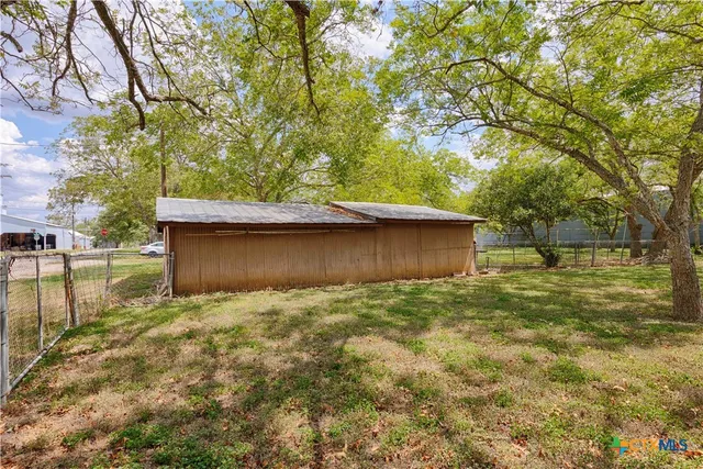 a backyard of a house with lots of plants and large trees