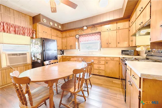 a kitchen with stainless steel appliances granite countertop a table chairs and a refrigerator