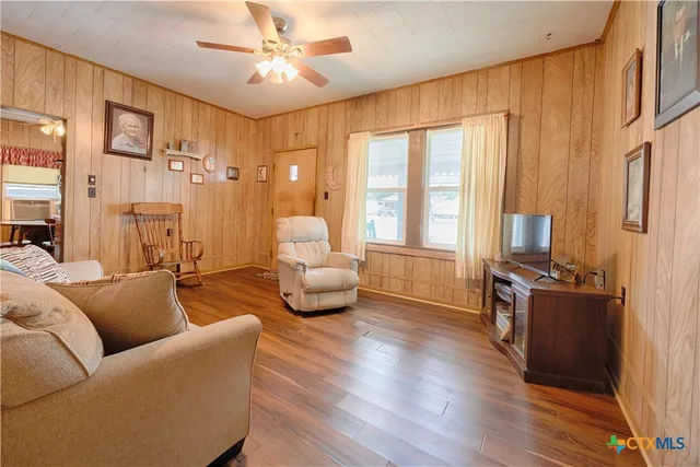 a living room with furniture floor to ceiling window and wooden floor