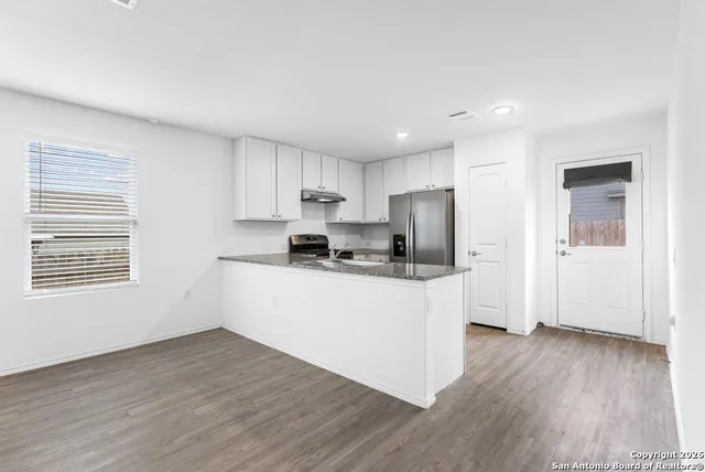 a kitchen with granite countertop white cabinets and wooden floor