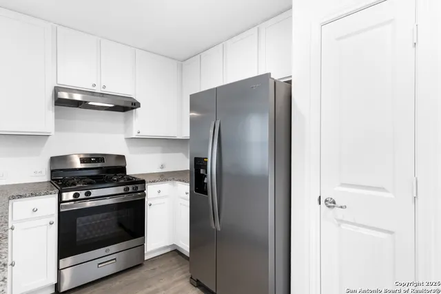 a kitchen with stainless steel appliances granite countertop a refrigerator and a stove