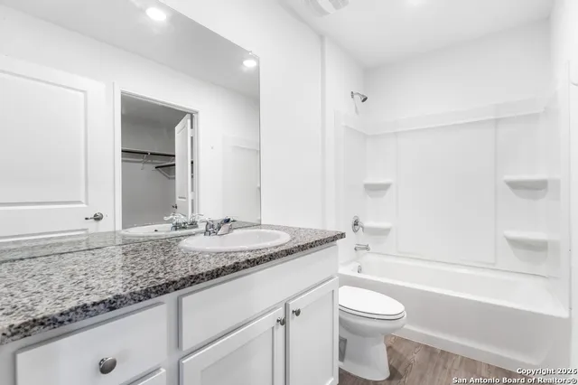 a bathroom with a granite countertop sink toilet mirror and bathtub
