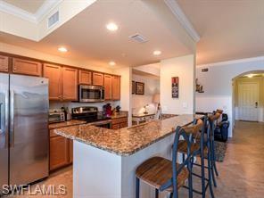 9723 Acqua Court, Unit 332 Naples, FL 34113 - Photo 5 of 23 a kitchen with granite countertop stainless steel appliances a refrigerator a stove a dining table and chairs