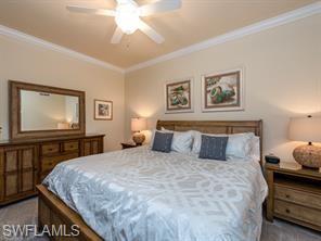 9723 Acqua Court, Unit 332 Naples, FL 34113 - Photo 8 of 23 a bedroom with a bed and a chandelier