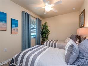 9723 Acqua Court, Unit 332 Naples, FL 34113 - Photo 10 of 23 a bedroom with a large bed and a chandelier